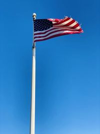 Low angle view of flag against blue sky