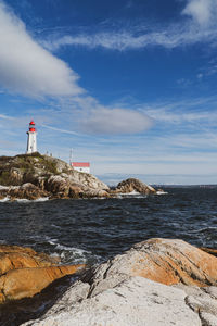 View of lighthouse by sea against sky