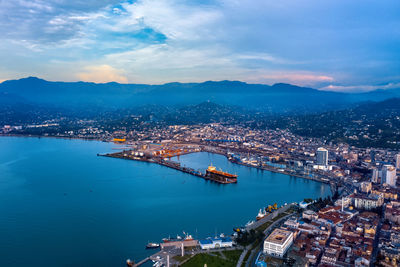 High angle view of illuminated city by sea against sky