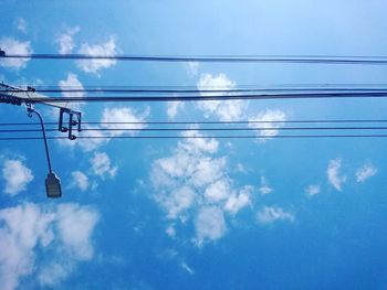 Low angle view of power cables against blue sky