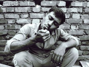 Young man smoking cigarette while sitting outdoors