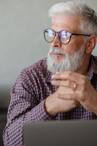 Businessman with hands clasped sitting against wall