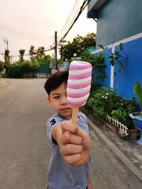 Portrait of boy holding sweet food on street