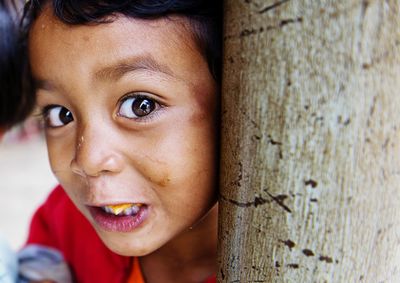 Close-up portrait of cute baby boy against tree trunk