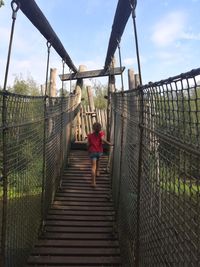 Rear view of girl walking on footbridge