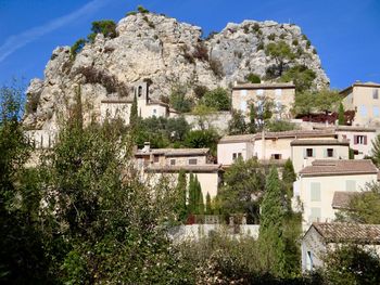 Old village by trees and rocks against sky