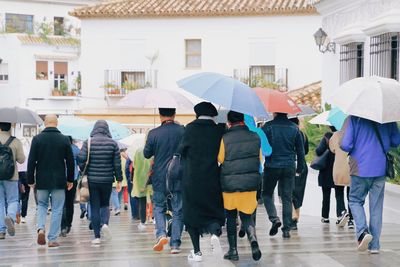 Rear view of people walking in rain