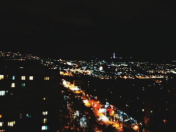 Illuminated cityscape against sky at night