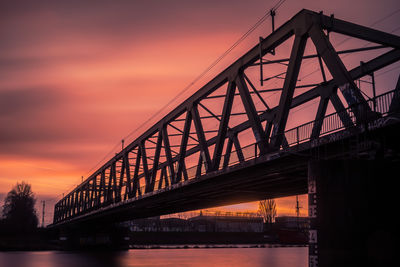 Low angle view of bridge over river at sunset