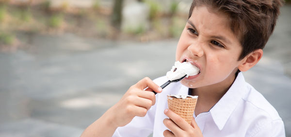 Cute child boy with a dirty face eats ice cream, the child enjoys dessert