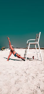Low angle view of young woman stretching on beach