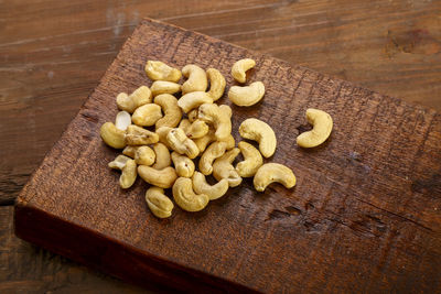 Cashew nuts scattered on a square board on a wooden table. horizontal photo