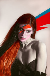 Portrait of young woman standing against wall