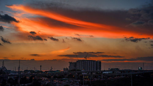 Silhouette buildings against dramatic sky during sunset