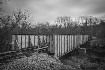 Railroad tracks by bare trees against sky
