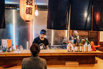 Full length of man sitting on table in restaurant