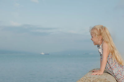 Little girl in sea against sky