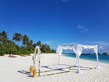 Chairs on beach against blue sky