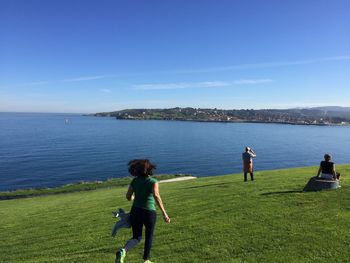 Rear view of man standing on grass by sea