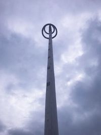 Low angle view of communications tower against cloudy sky