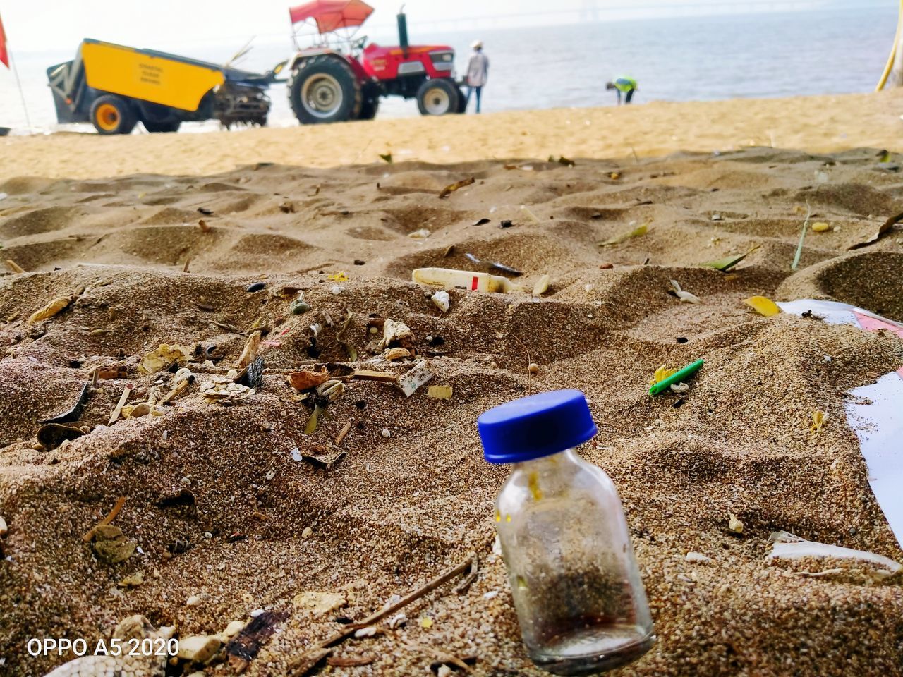 CLOSE-UP OF PLASTIC BOTTLE ON BEACH