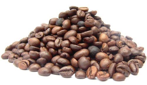 Close-up of roasted coffee beans against white background