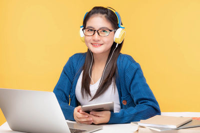 Young woman using mobile phone while sitting on table