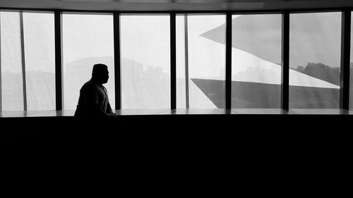 Side view of silhouette man standing against window