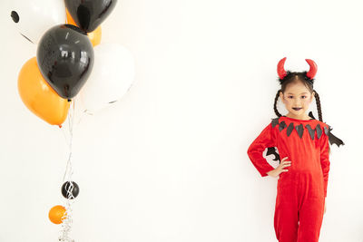 Portrait of girl with balloons standing against white background