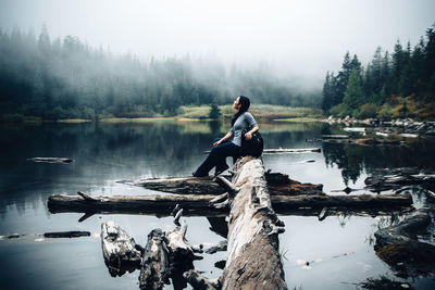 Women relaxing on log on lake