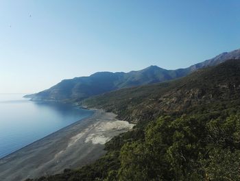 Scenic view of sea and mountains against clear blue sky