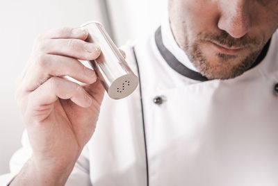 Midsection of chef holding salt shaker in kitchen