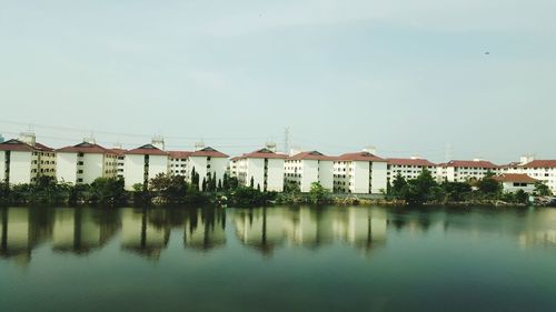 Buildings by lake against sky