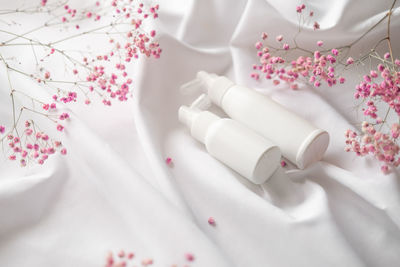 White plastic dispenser mockup, shampoo or facial cleanser on a white background among delicate pink