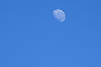 Low angle view of moon against clear blue sky