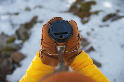 Paper cup in hands in mittens, in nature on a background of snow