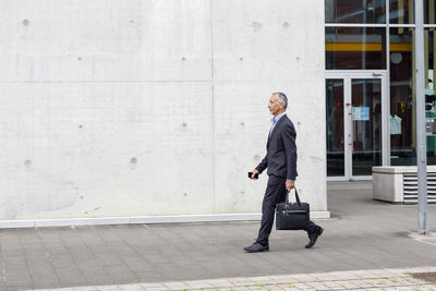 Male business professional with briefcase walking near office building