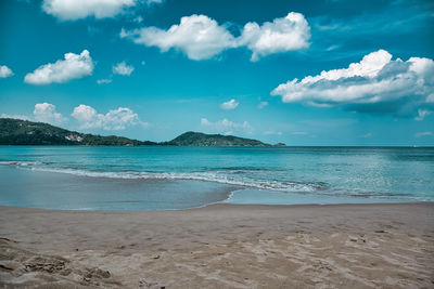 Empty, calm sandy crescent patong beach with turquoise blue clear water and cirrus cloudy sky