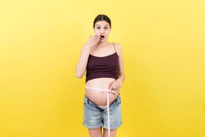 Portrait of woman standing against yellow background