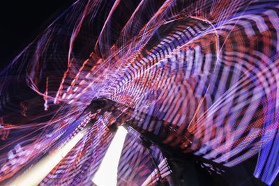 Blurred motion of illuminated amusement park ride at night