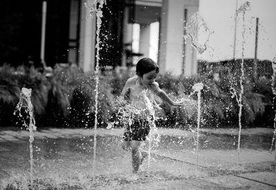 Full length of shirtless boy playing in water