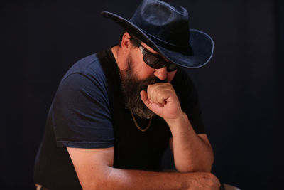 Portrait of young man wearing hat against black background