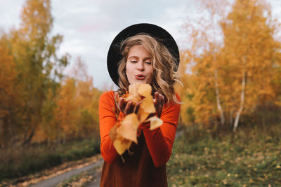 A pretty girl enjoys solitude drinks coffee walks in the autumn forest in nature in fall