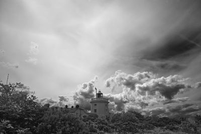 Lighthouse amidst buildings against sky