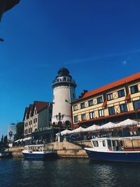 Buildings by river against blue sky