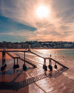 Bridge over river in city against sky during sunset