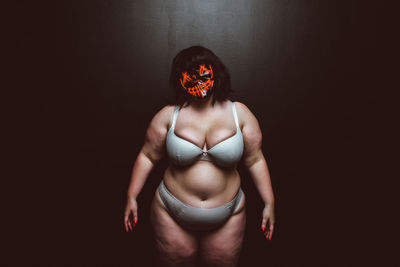 Woman wearing mask against black background