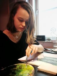 Young woman looking away while sitting on table