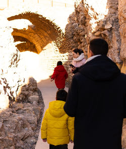 Rear view of people walking in tunnel