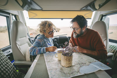 Happy couple looking at map sitting in motor home